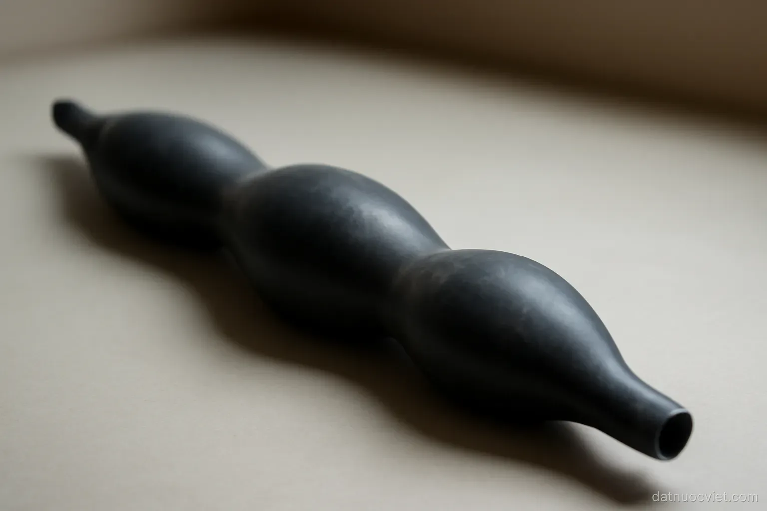 Long inflated rubber tube lying on a flat surface with two bulges along its length, thin sections in between